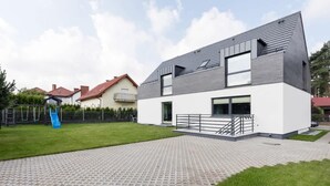 Una casa moderna de dos pisos con techo plano, ventanas amplias y entrada pavimentada.