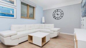 Una sala de estar moderna con un sofá seccional blanco, una mesa de centro de madera y un reloj de pared grande.