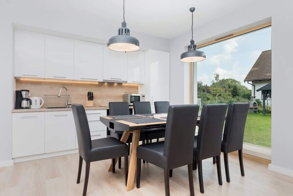 A modern kitchen with white cabinets, a wooden dining table, and black chairs.