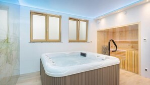 Un baño moderno con una bañera independiente grande, armarios de madera y un box de ducha de cristal.