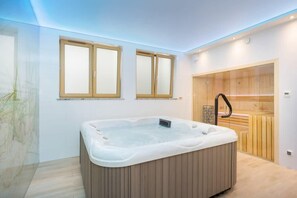 Un baño moderno con una bañera independiente grande, armarios de madera y un box de ducha de cristal.