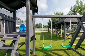 A wooden play structure with swings and a slide.
