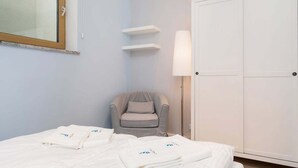 Una habitación de hotel con cama, una silla, armario y espejo.