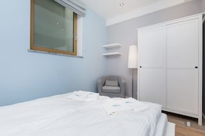 A bedroom with a bed, a chair, a wardrobe, and a window.