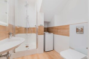 A modern bathroom with a glass-enclosed shower, a white sink, and a toilet.