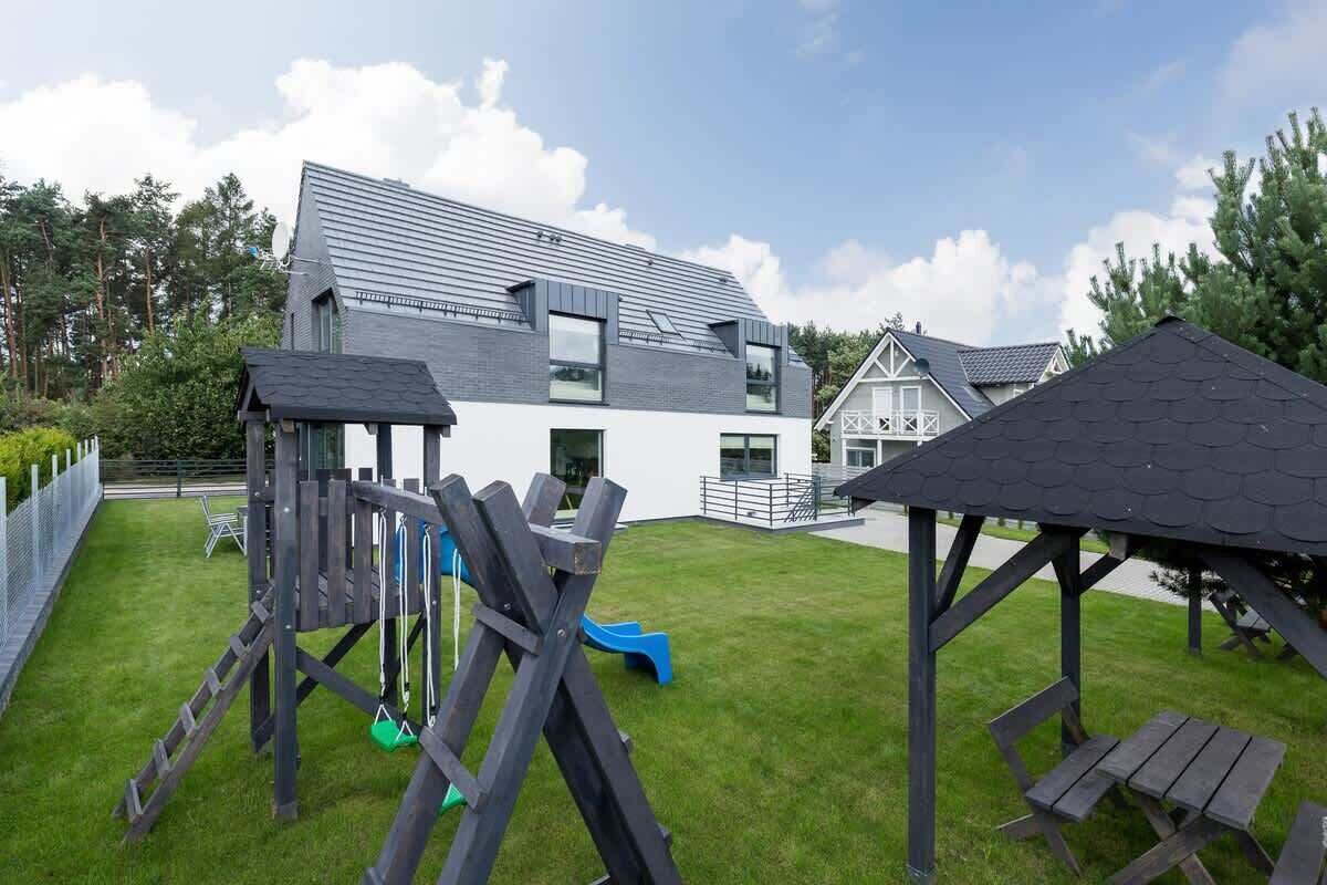 Une maison moderne dotée d’une grande terrasse, d’un toboggan et d’un belvédère.