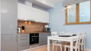 A modern kitchen with grey cabinets, a wooden countertop, and a dining table with chairs.
