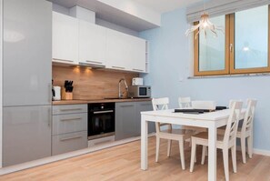 Una cocina moderna con armarios grises, encimera de madera y una mesa de comedor con sillas.