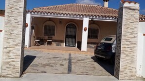 Un edificio con techo de tejas, pilares de piedra y un coche estacionado adelante.