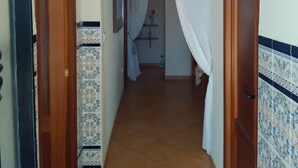 Un pasillo con paredes y piso de baldosas, y una lámpara en el techo.