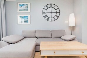 Un salon moderne avec un canapé gris, une table basse en bois et une horloge murale.