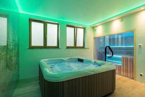 A modern bathroom with a hot tub, large windows, and a view of a pool.