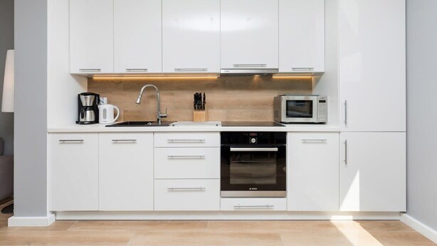 Eine moderne Küche mit weißen Schränken, einem Bosch-Backofen, einer Mikrowelle und einer Kaffeemaschine.