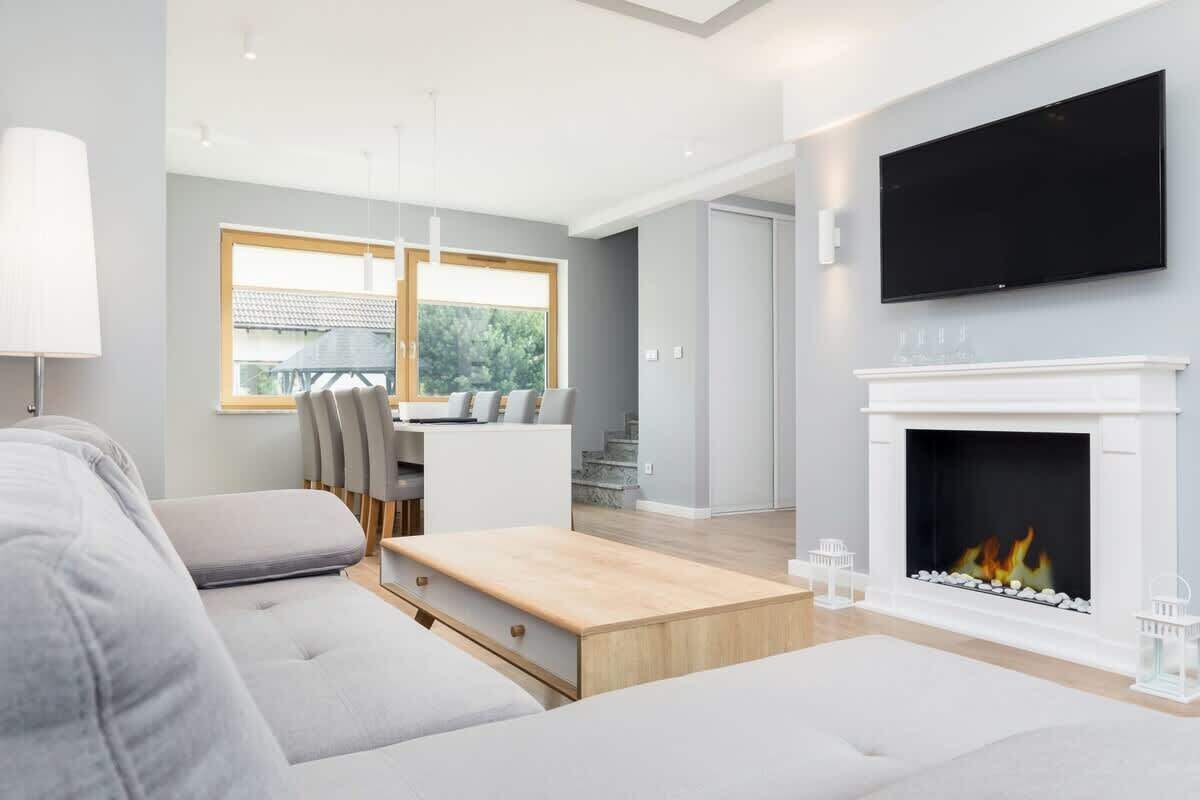 A modern living room with a fireplace, a flat-screen TV, and a dining area with a table and chairs.