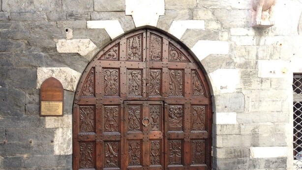 A stone building with a large wooden door featuring intricate carvings.
