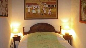 A bedroom with a wooden bed, two bedside lamps, and a painting on the wall.