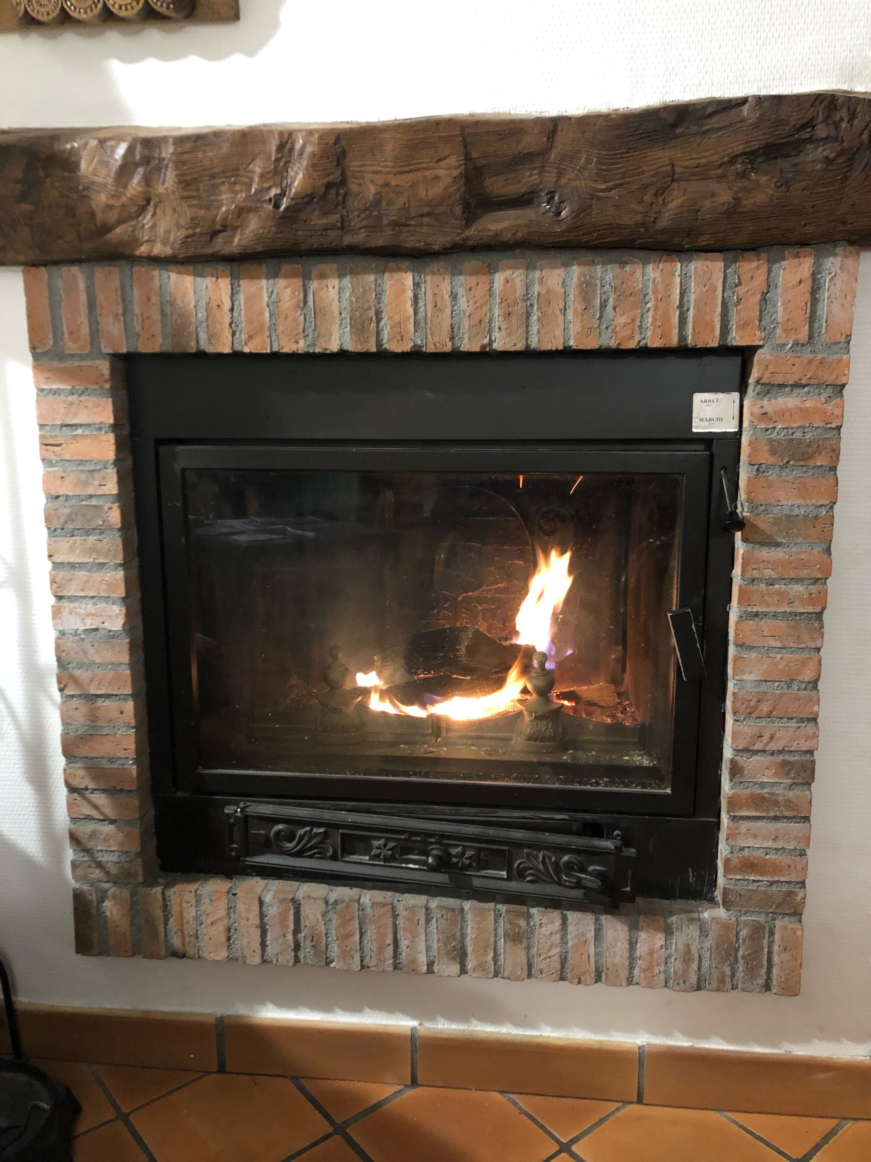 A fireplace with a brick surround and a wooden mantel.