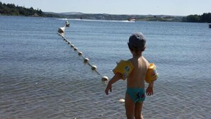 A child standing in a lake with a floating path of buoys. - Cottage of the Barry fountain in Aveyron (Le Vibal)