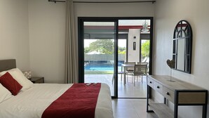 Une chambre d’hôtel avec un lit, un bureau et une vue sur une piscine extérieure.