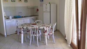 Een keuken met een eettafel, stoelen, een koelkast en een hanglamp.