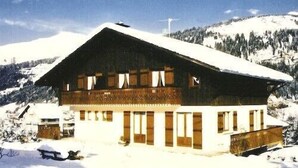A chalet-style building with a sloped roof, wooden exterior, and multiple windows. - 1st floor apartment in Savoyard chalet in Morzine. (Morzine)