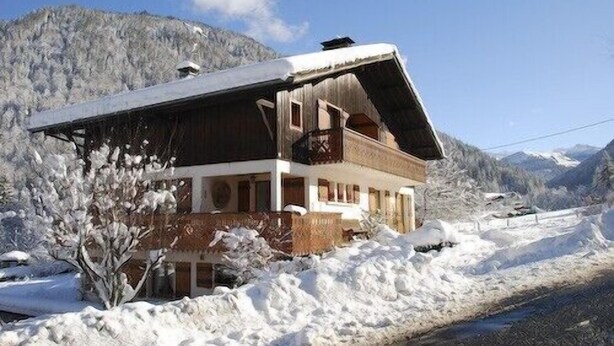 A chalet with a sloped roof, wooden exterior, and a balcony. It is surrounded by snow and mountains. - 1st floor apartment in Savoyard chalet in Morzine. (Morzine)