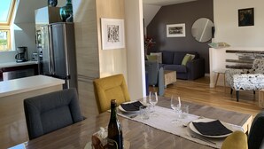 A modern kitchen with a refrigerator, a dining table set for two, and a living area with a sofa and a coffee table. -  Fisherman's house with exceptional view of the back port, close to the beaches (Treffiagat)