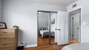 A bedroom with a sliding door leading to a bathroom, a wooden dresser, and a bed with a gray bedspread. - Old Town Scottsdale - With a pool, hot tub,  Putting Green, Billiards. (Scottsdale)