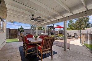 A covered patio area with a table and chairs, a ceiling fan, and a view of the backyard. - Old Town Scottsdale - With a pool, hot tub, Putting Green, Billiards. (Scottsdale)