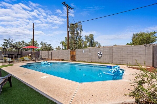 A rectangular swimming pool with a tiled deck, surrounded by a low brick wall, and a wooden gate. - Old Town Scottsdale - With a pool, hot tub, Putting Green, Billiards. (Scottsdale)