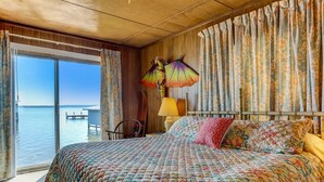 Ein Schlafzimmer mit einem großen Bett, floralen Vorhängen und Blick aufs Wasser.