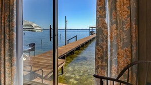 Blick von einem Zimmer mit einer Holzterrasse, die über dem Wasser liegt, inklusive Stuhl und Tisch.
