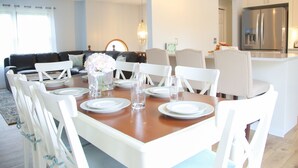 Comedor con una mesa de madera dispuesta para seis personas, rodeado de sillas blancas.