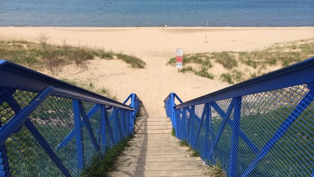 Una escalera que lleva a una playa con vistas despejadas del océano.