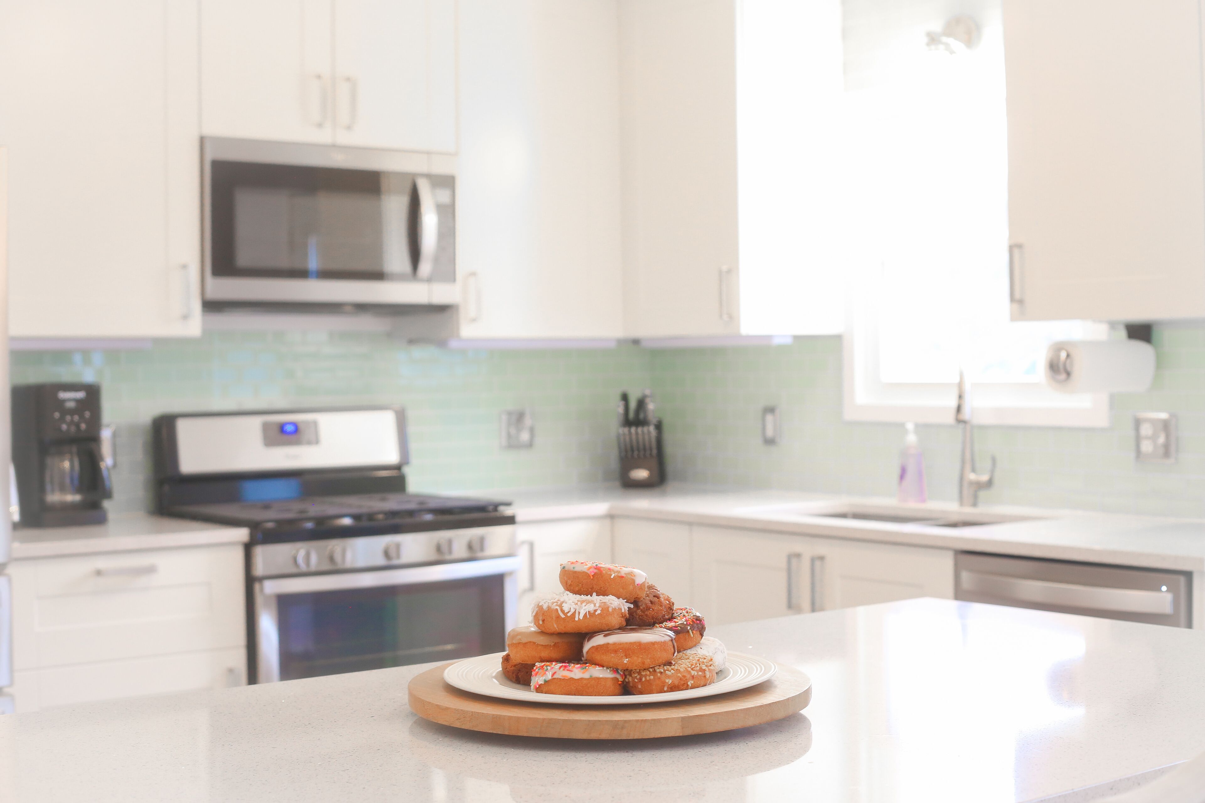 A kitchen with white cabinets, a microwave, a stove, and a sink.