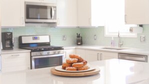Una cocina con armarios blancos, microondas, estufa y lavaplatos.