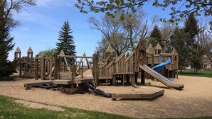 Un parque infantil de madera con un tobogán y estructuras para escalar.