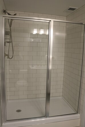 Een bad/douchecombinatie, een haardroger, handdoeken, toiletpapier