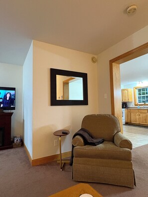 A living room with a television, a framed mirror, a small table, and a sofa.