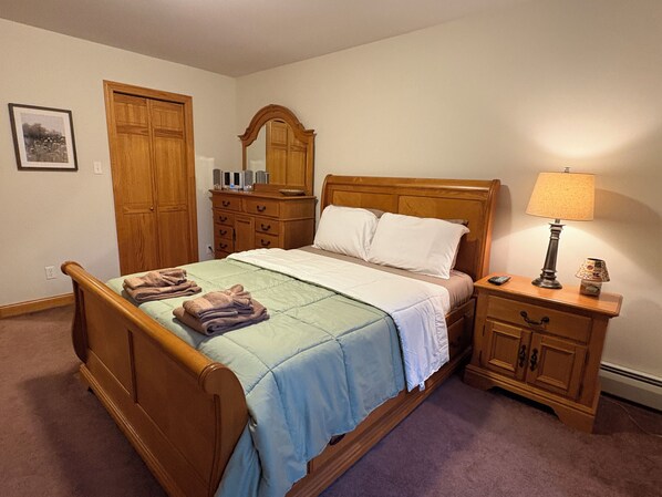 Une chambre à coucher comprenant un lit, une commode, une table de chevet, une lampe et un miroir.