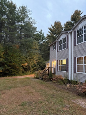 A two-story house with a front porch and a pathway leading to the entrance.