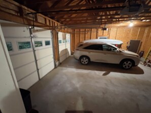 A car parked inside a garage with wooden walls and a concrete floor.