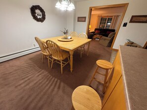 A dining area with a wooden table and chairs, a vase with flowers, and a chandelier.