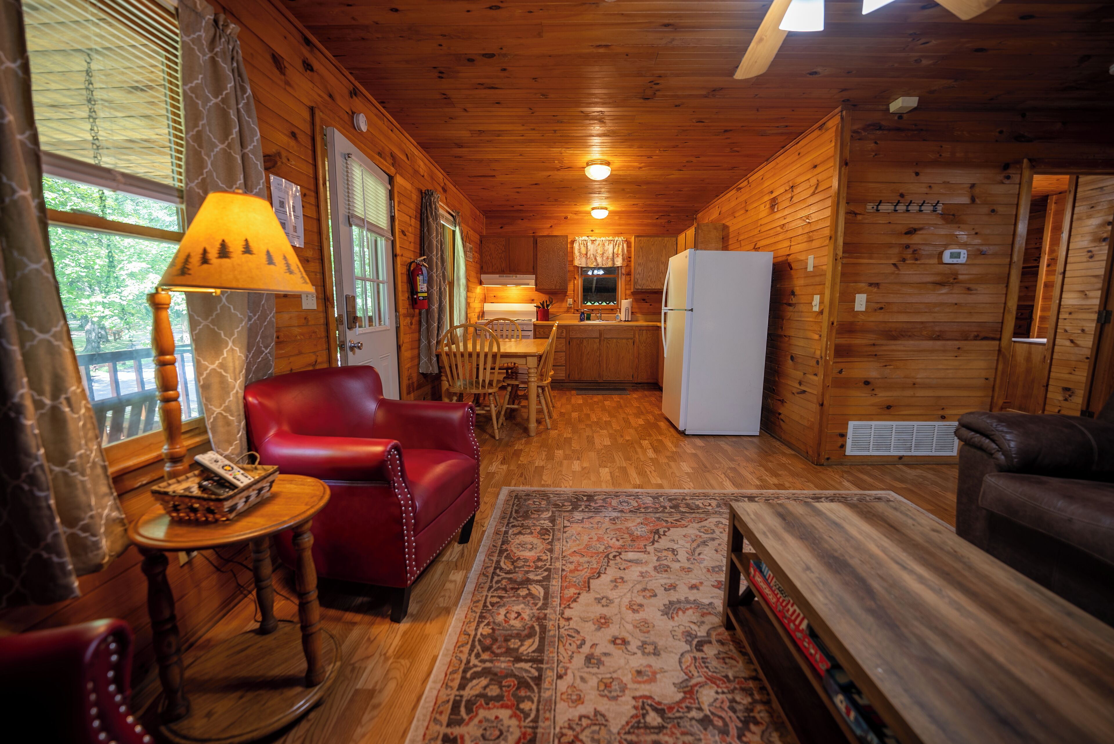 A cabin interior with a dining area, kitchen, and seating space.