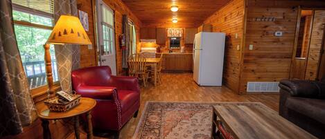 A cabin interior with a dining area, kitchen, and seating space.