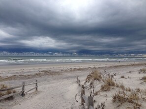 Une plage avec une clôture en bois et des dunes.