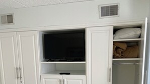 A white wardrobe with a television, drawers, and a shelf with a blanket. - Direct Beachfront Condo With Great Ocean Views From Couch Or On The Porch (North Wildwood)