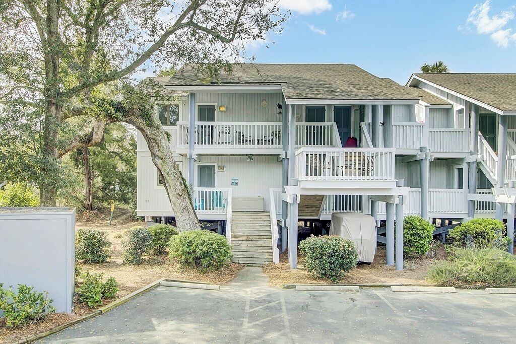 A two-story building with a balcony on the second floor, a covered staircase, and a small porch area.