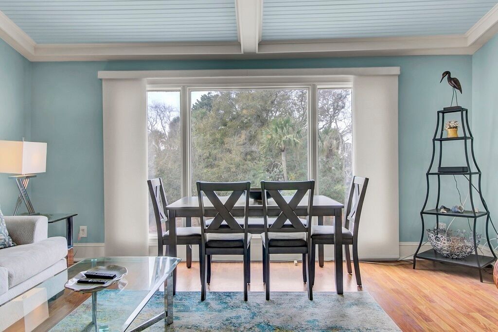A dining area with a table and chairs, a glass coffee table, a lamp, and a decorative shelf.