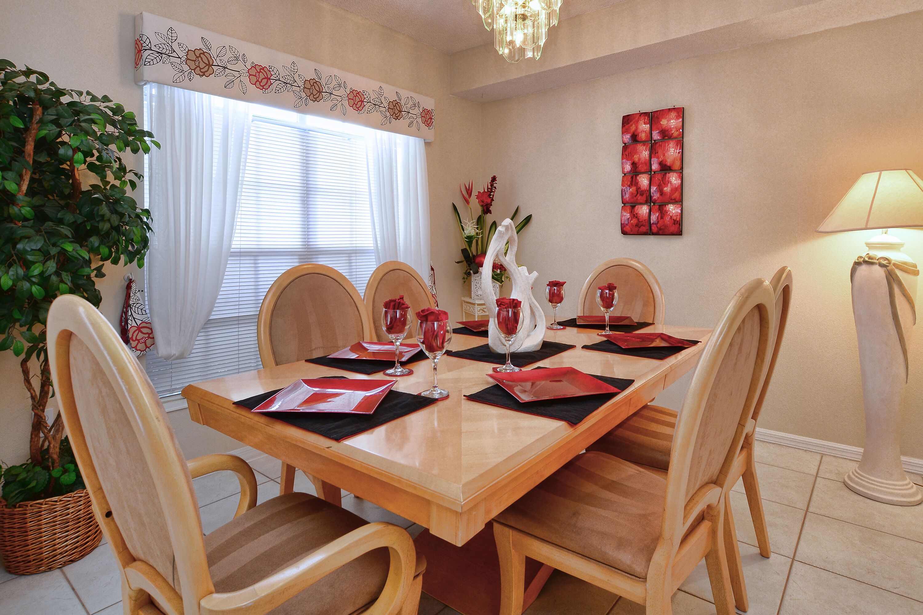 A dining room with a wooden table set for four, surrounded by wooden chairs.